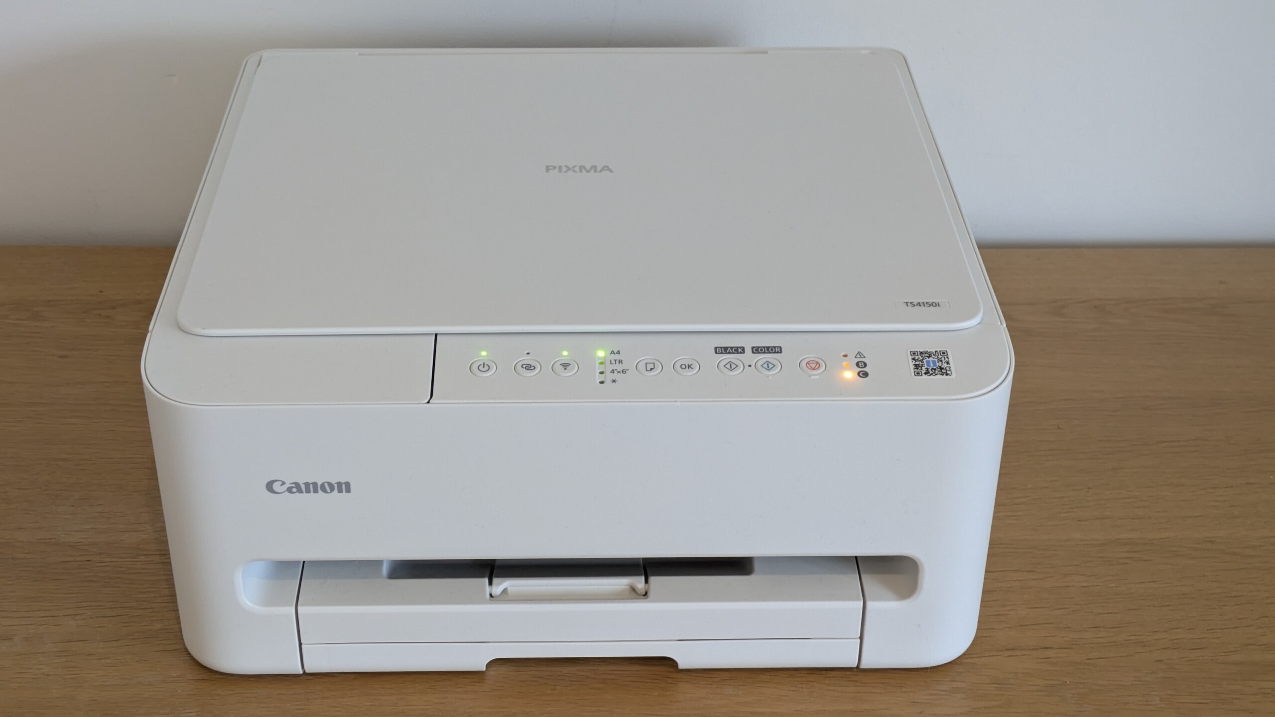A sleek Canon PIXMA TS4150i printer in a home office setting, ready for use.